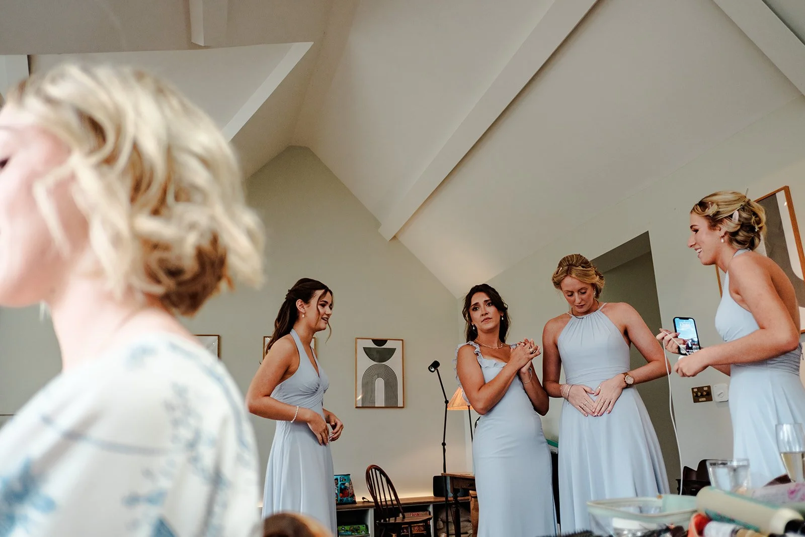 Bridesmaids in pale blue halter-neck dresses reacting with delight as Abi reveals her wedding dress at Limekiln
