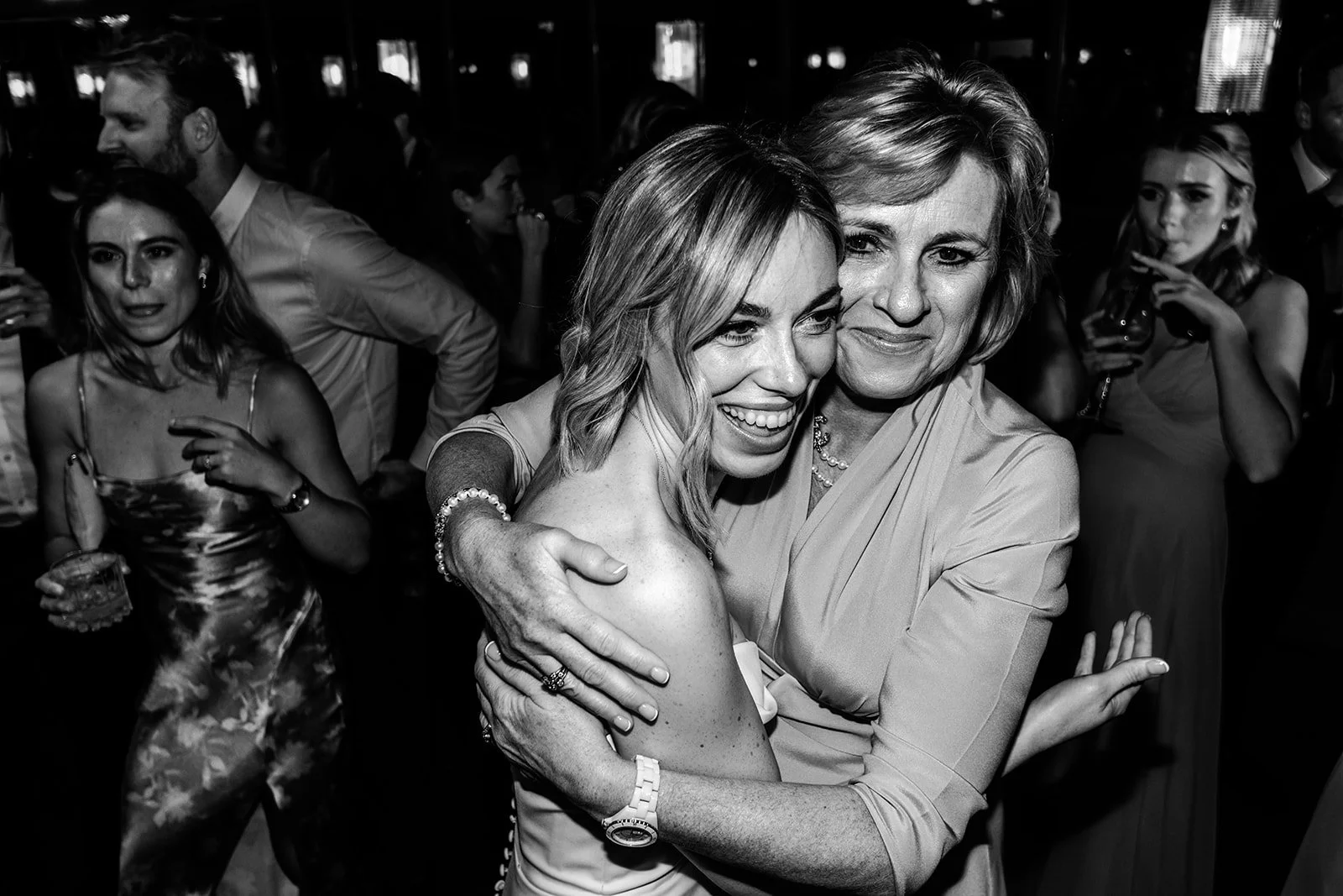 Abi embracing a friend on the Limekiln dance floor, both laughing with pure joy — black and white evening reception photograph