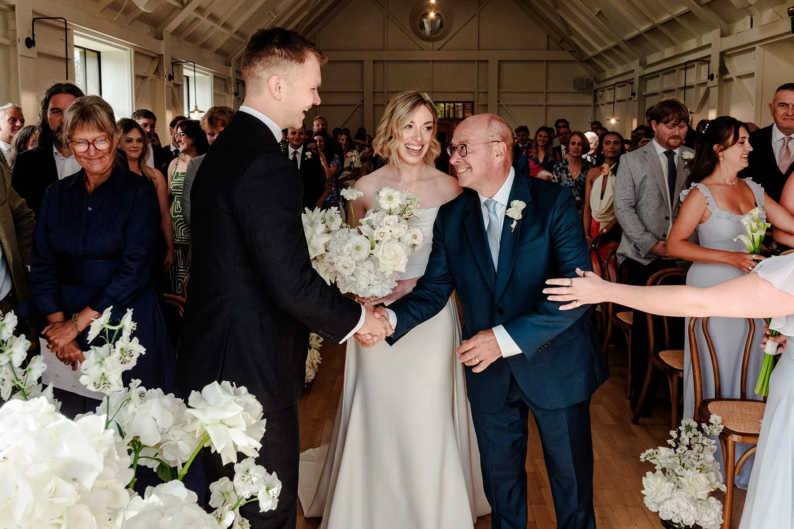 Abi's father shaking Jack's hand warmly as he gives her away at the altar inside Limekiln's ceremony barn — an emotional and tender moment