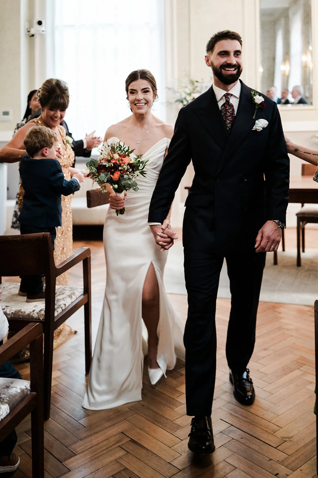 Newlyweds walking back down the aisle over the herringbone parquet floor at Chelsea Old Town Hall