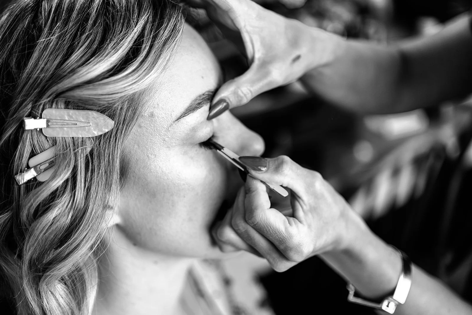 Close-up black and white detail of Abi's makeup being applied on the morning of her Limekiln wedding