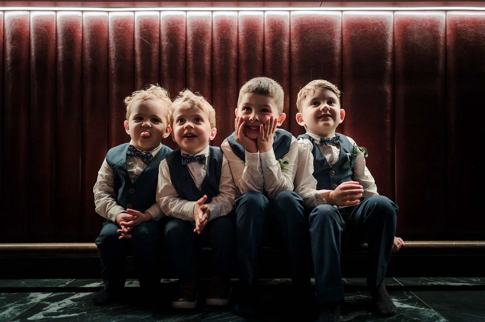 Four boys pulling faces in a velvet booth at The Other House