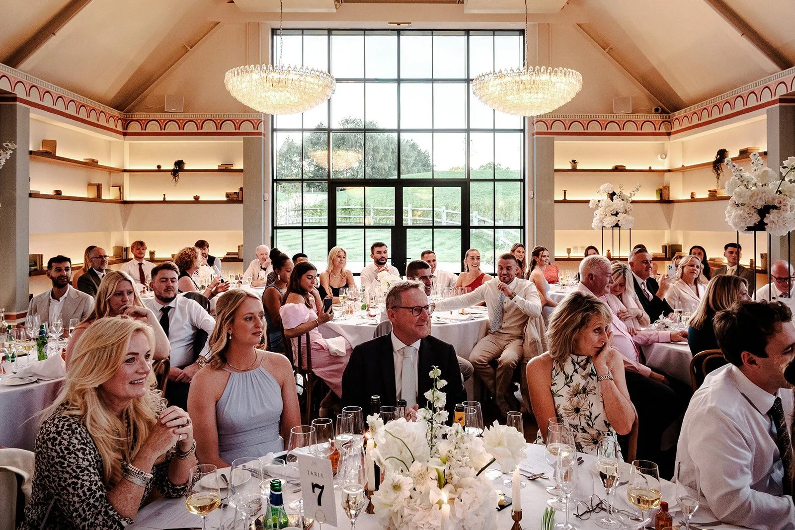 Wide shot of guests seated at the wedding breakfast at Limekiln, the stunning dining room filled with smiling faces and bright flowers