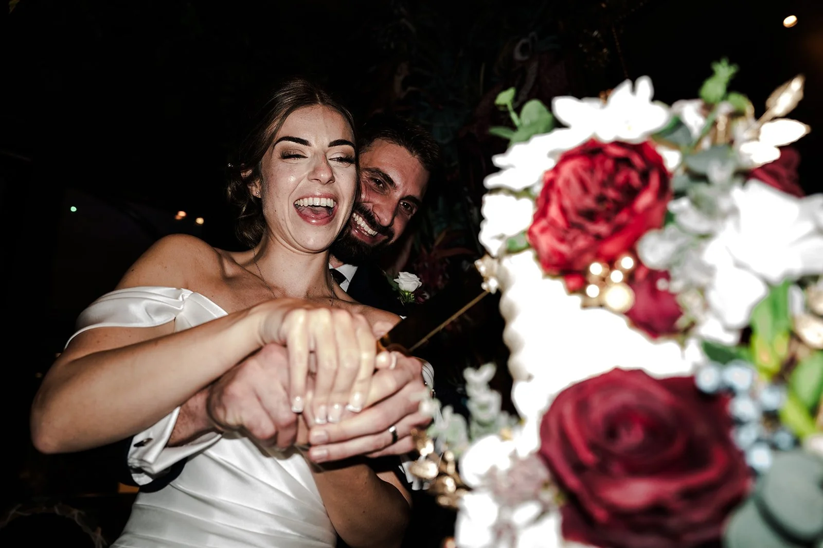 Nat and Josh cutting their wedding cake, laughing