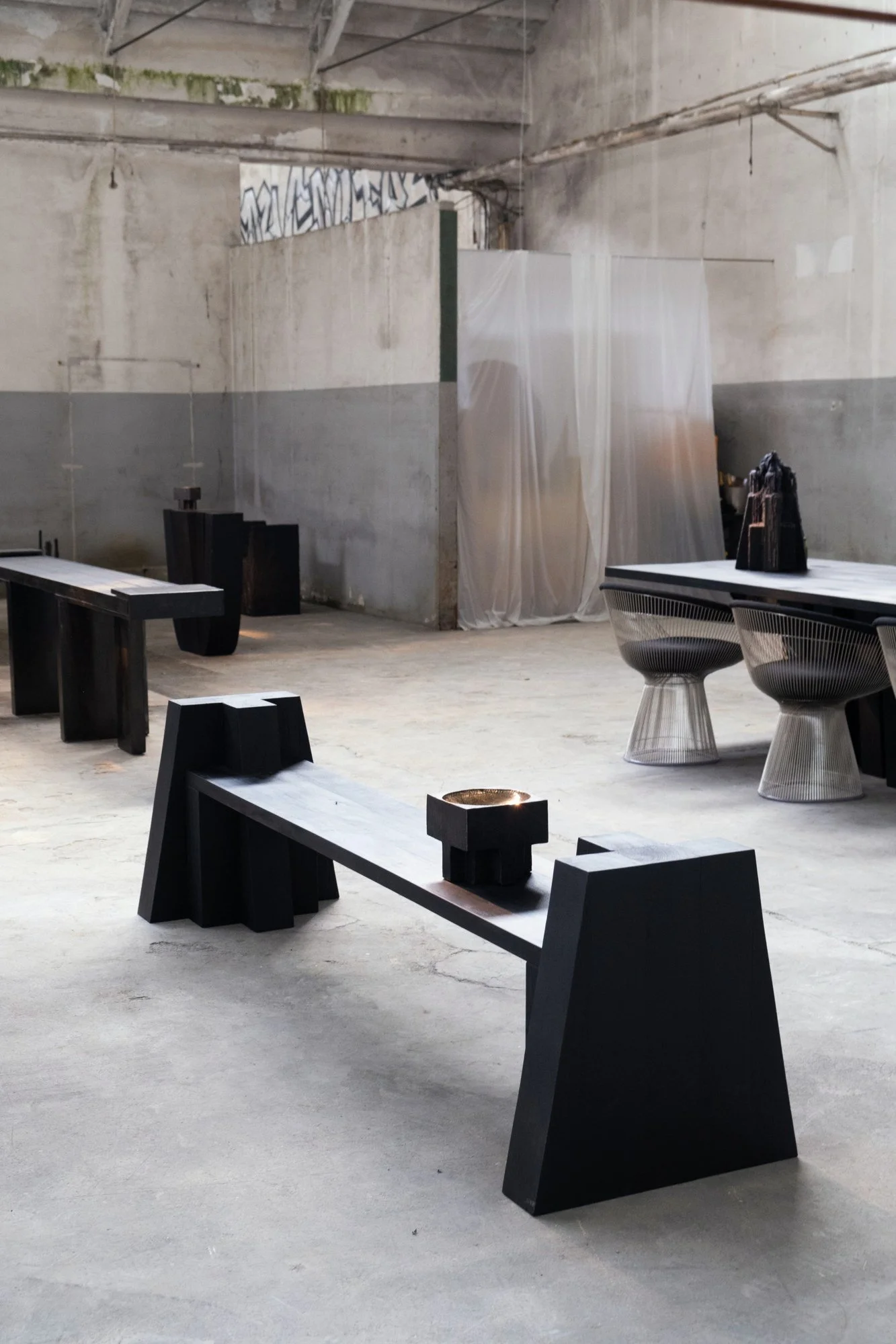 Sculptural furniture displayed in the industrial exhibition setting.