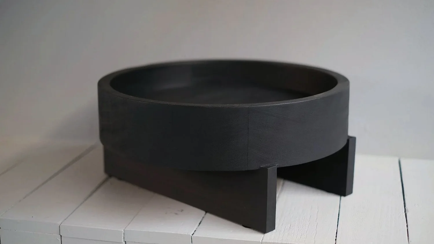 Closer view of the Iroko bowl and crossed base of the Double Slated Tray by Arno Declercq.