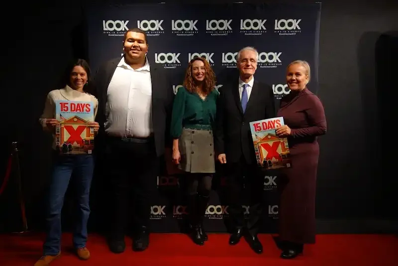 The 15 DAYS team and cast at the New York premiere, holding the film's poster