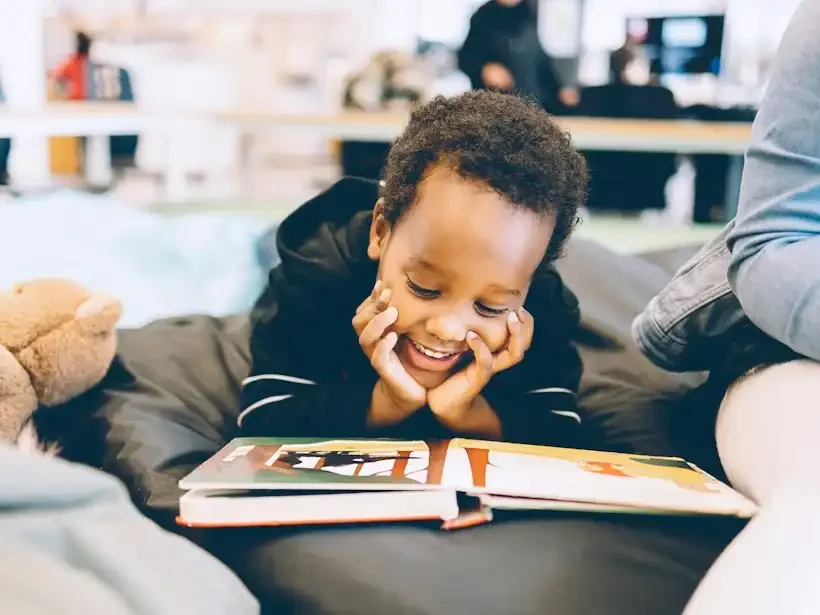 A boy smiles as he reads a picture book