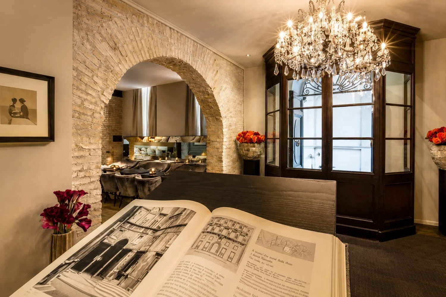 Lobby at D.O.M Hotel with a crystal chandelier and brick arch
