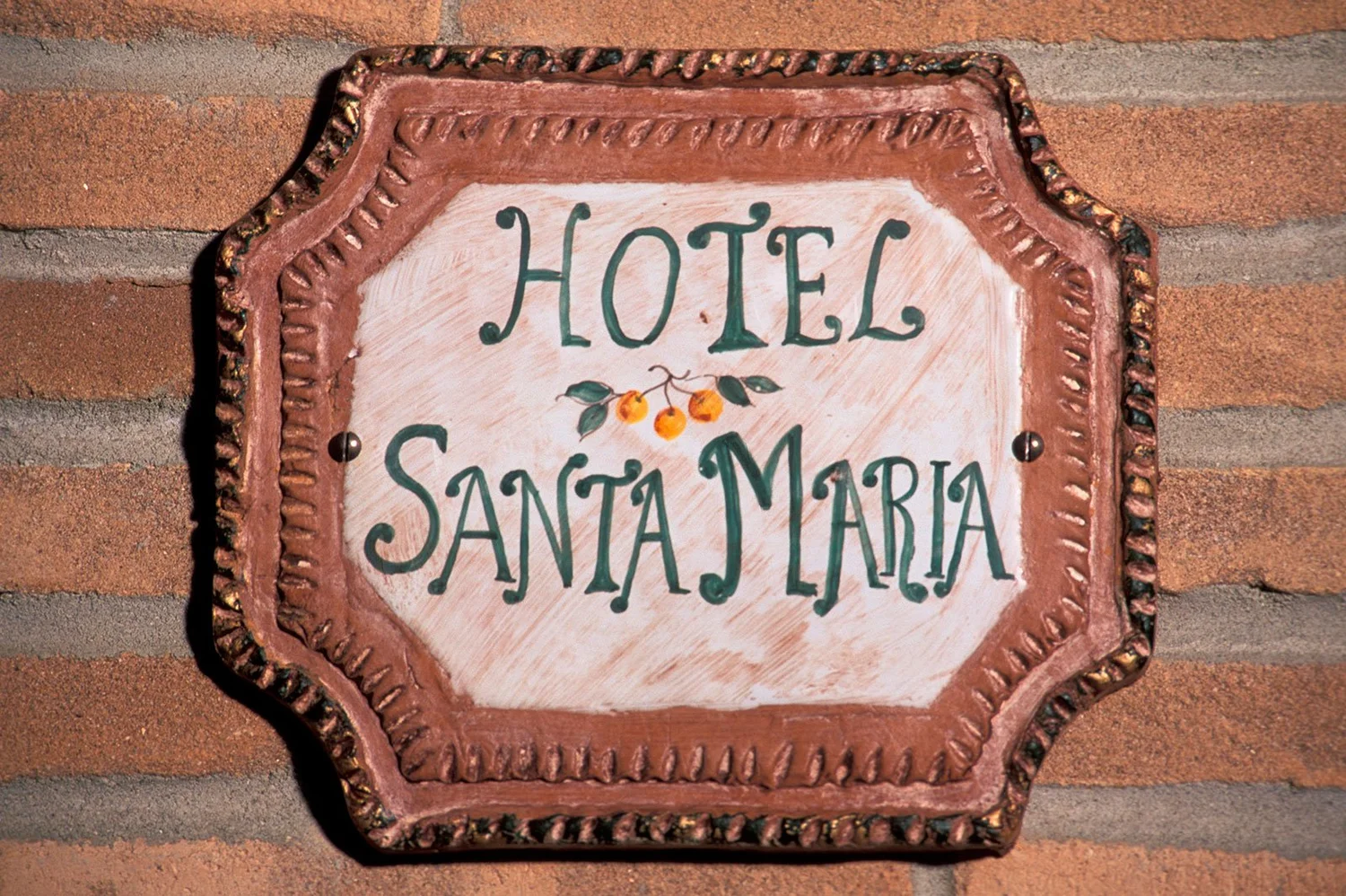 Hand-painted ceramic Hotel Santa Maria sign on a brick wall
