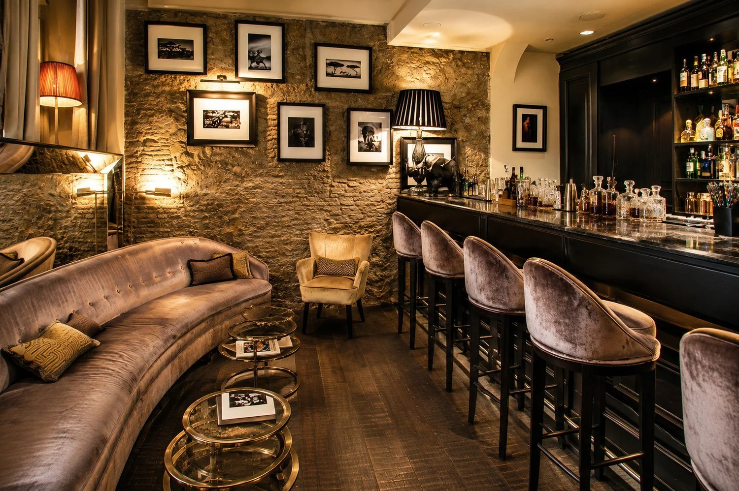 Bar at D.O.M Hotel with velvet stools and a stone wall