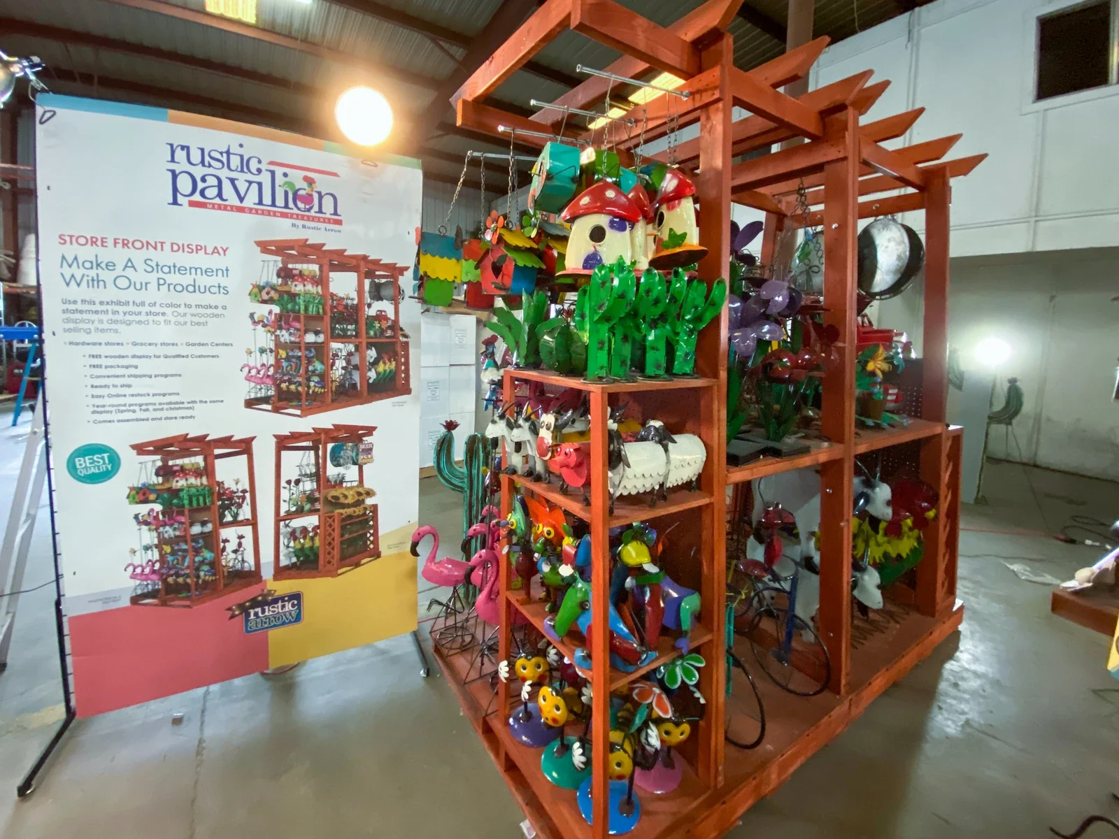 Full-size Rustic Pavilion Display stocked with colorful metal garden products beside a product presentation board.
