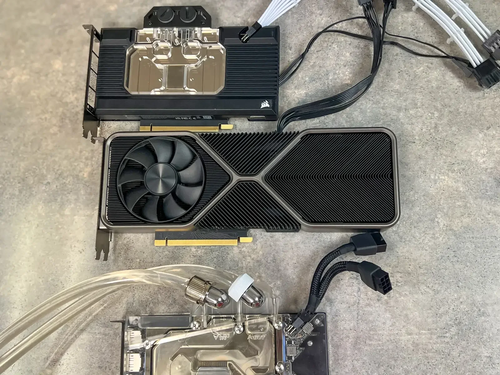Graphics cards, custom water blocks, cooling lines and power leads arranged on a work surface.