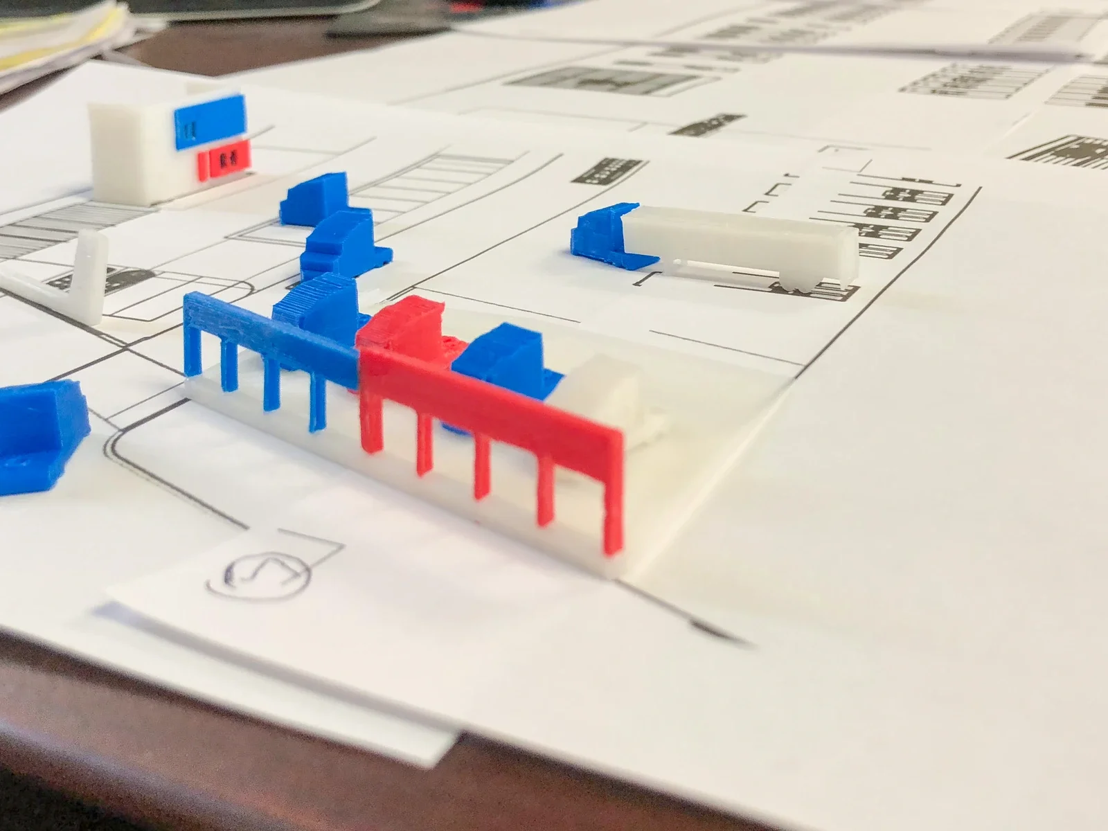 Small colored site-model components positioned over a paper plan.