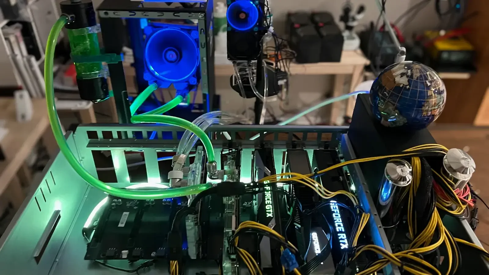 Open-frame multi-GPU computer with green liquid-cooling tubes and illuminated fans.