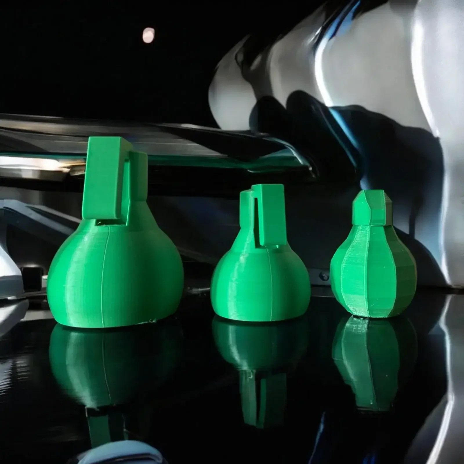 Three green 3D-printed prototype objects showing different shapes and surface finishes