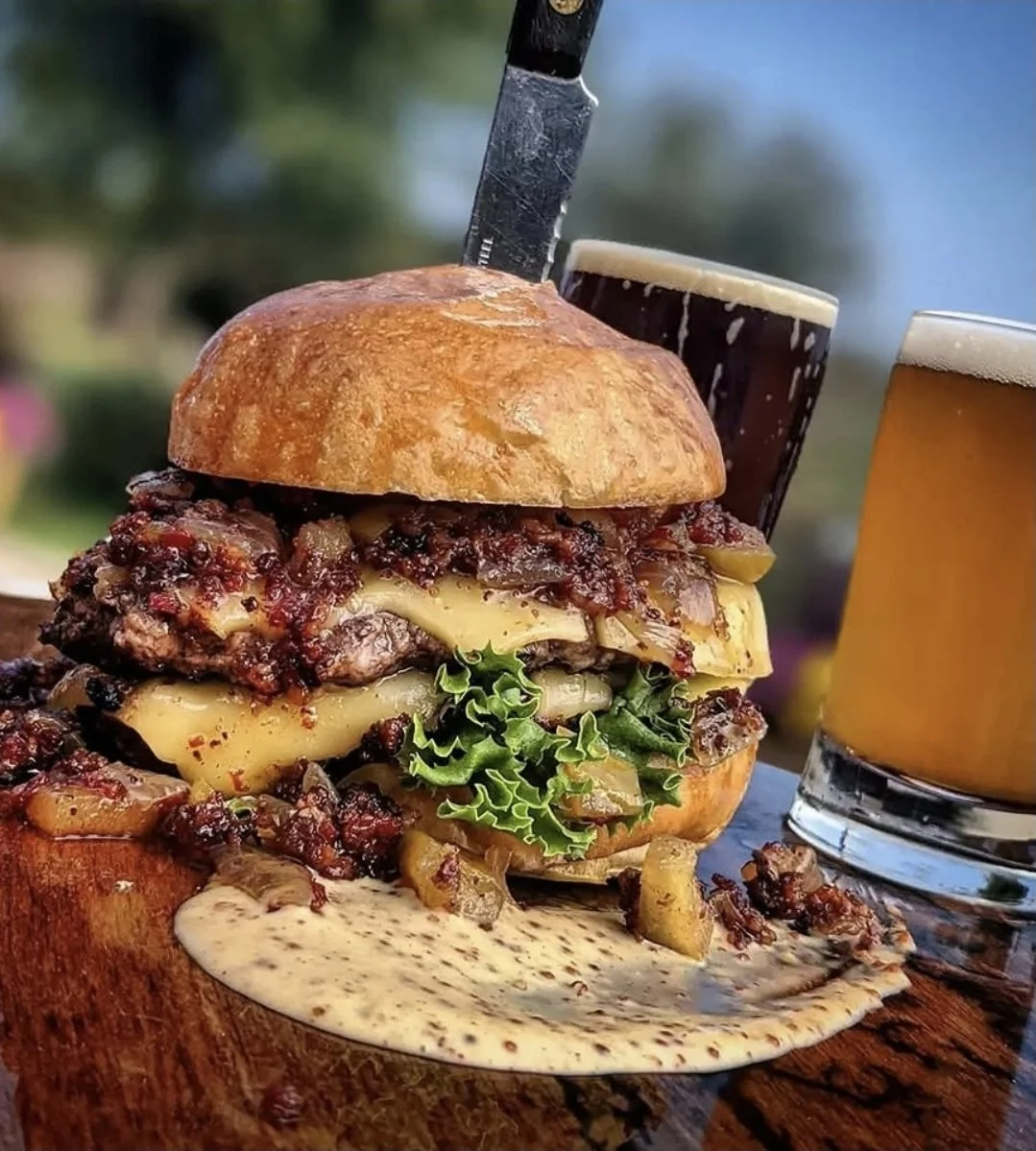 A double cheeseburger from Hawks Hill Grill next to two pints of beer