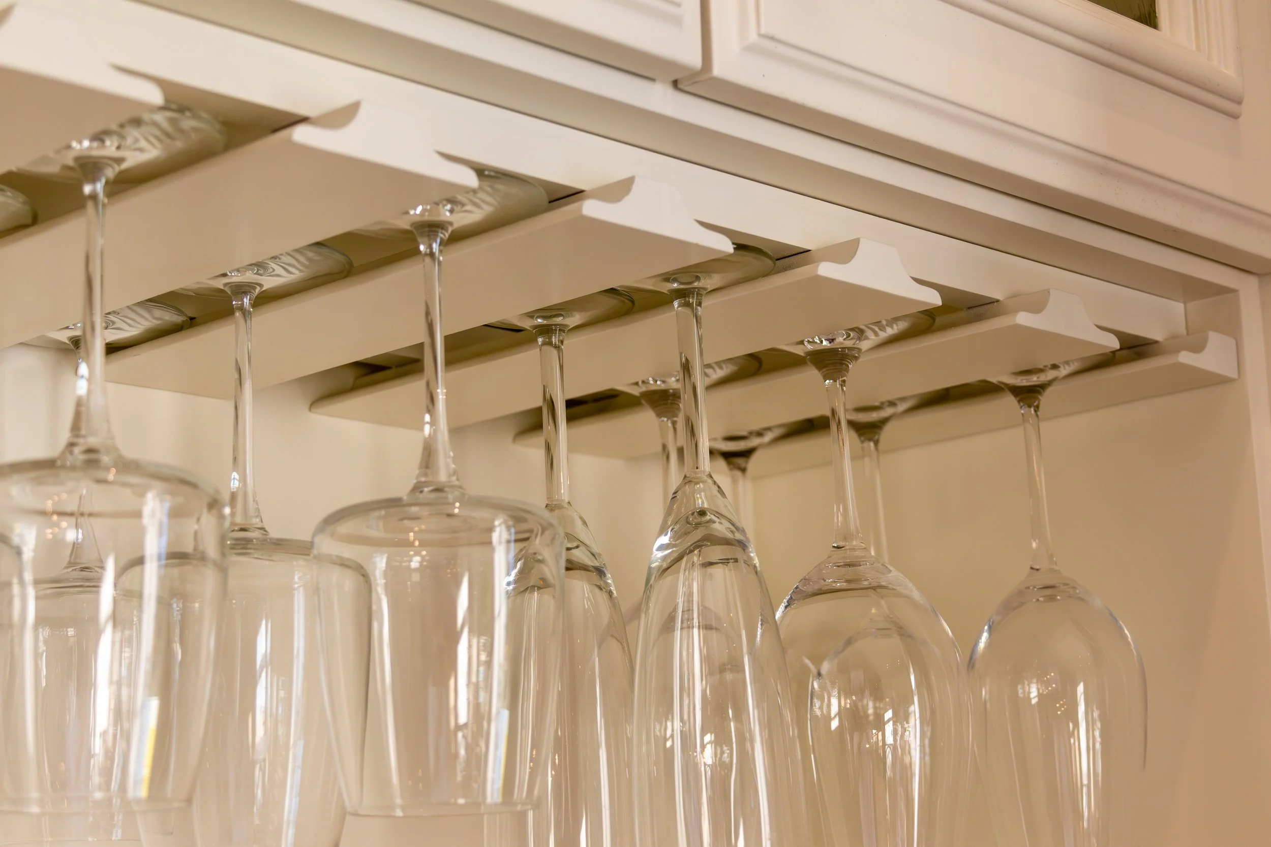 Close-up of cream-painted built-in cabinetry with an integrated rack holding wine glasses