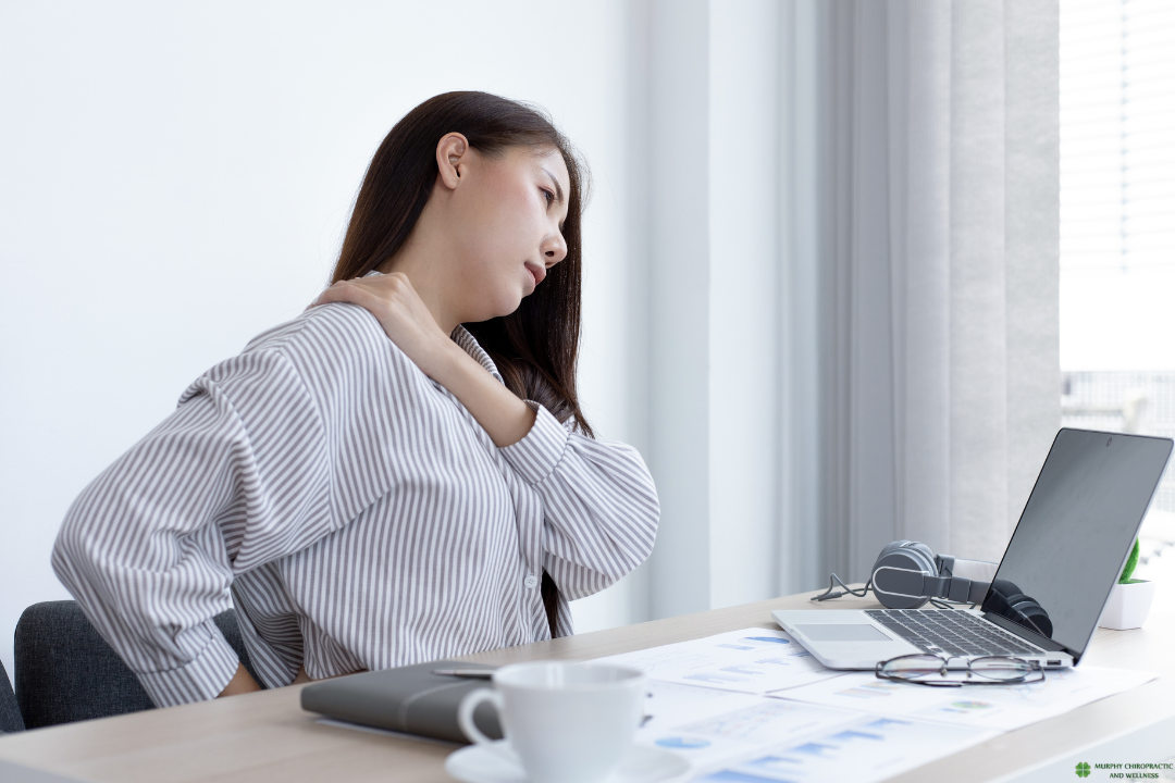 Office worker experiencing upper back tension between shoulder blades