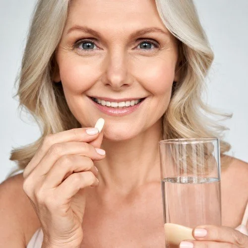 Smiling woman holding a supplement and a glass of water