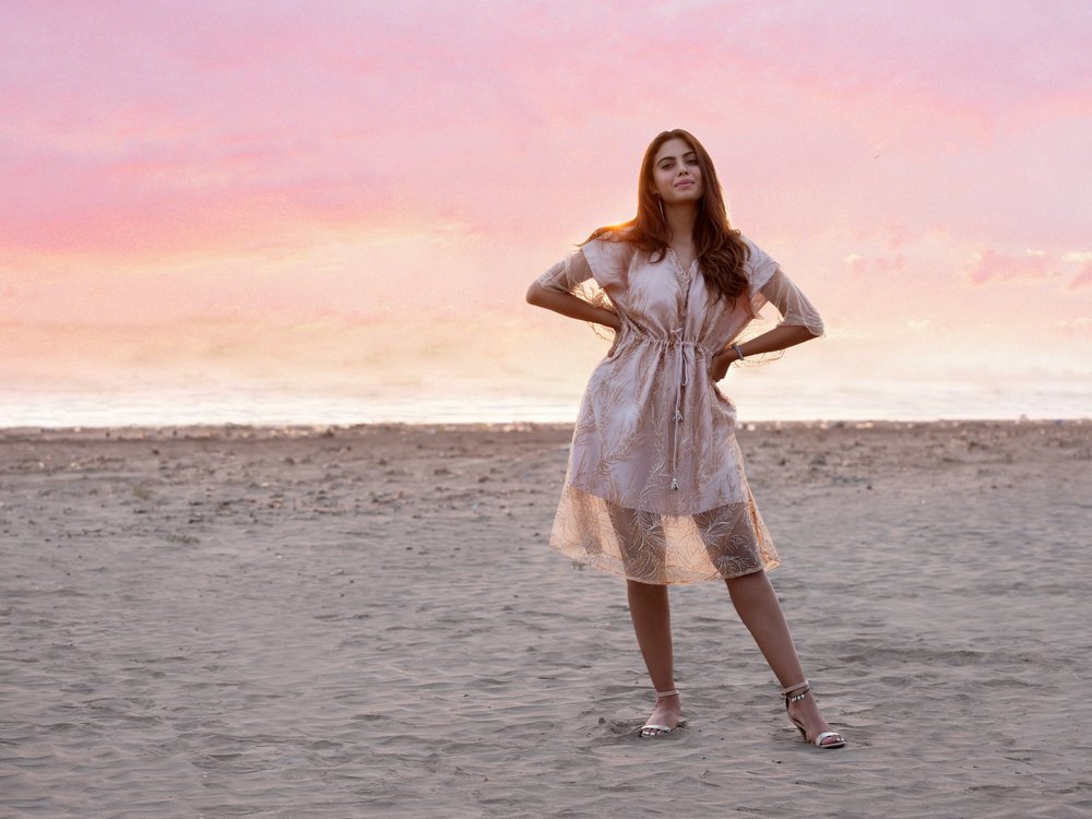 Zanzibar Kaftan photographed on the beach at dusk, with hands at the waist.