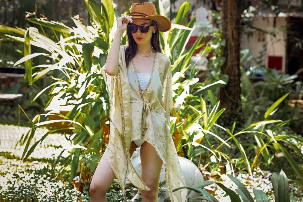 Golden Radiance Kaftan in garden sunlight, with its beaded neckline and sleeves visible.