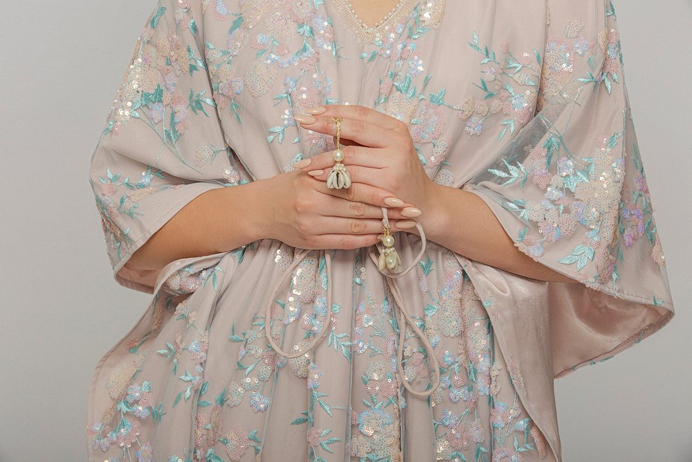 Studio detail of the Mykonos Kaftan showing the dimensional floral ornament and gathered waist.