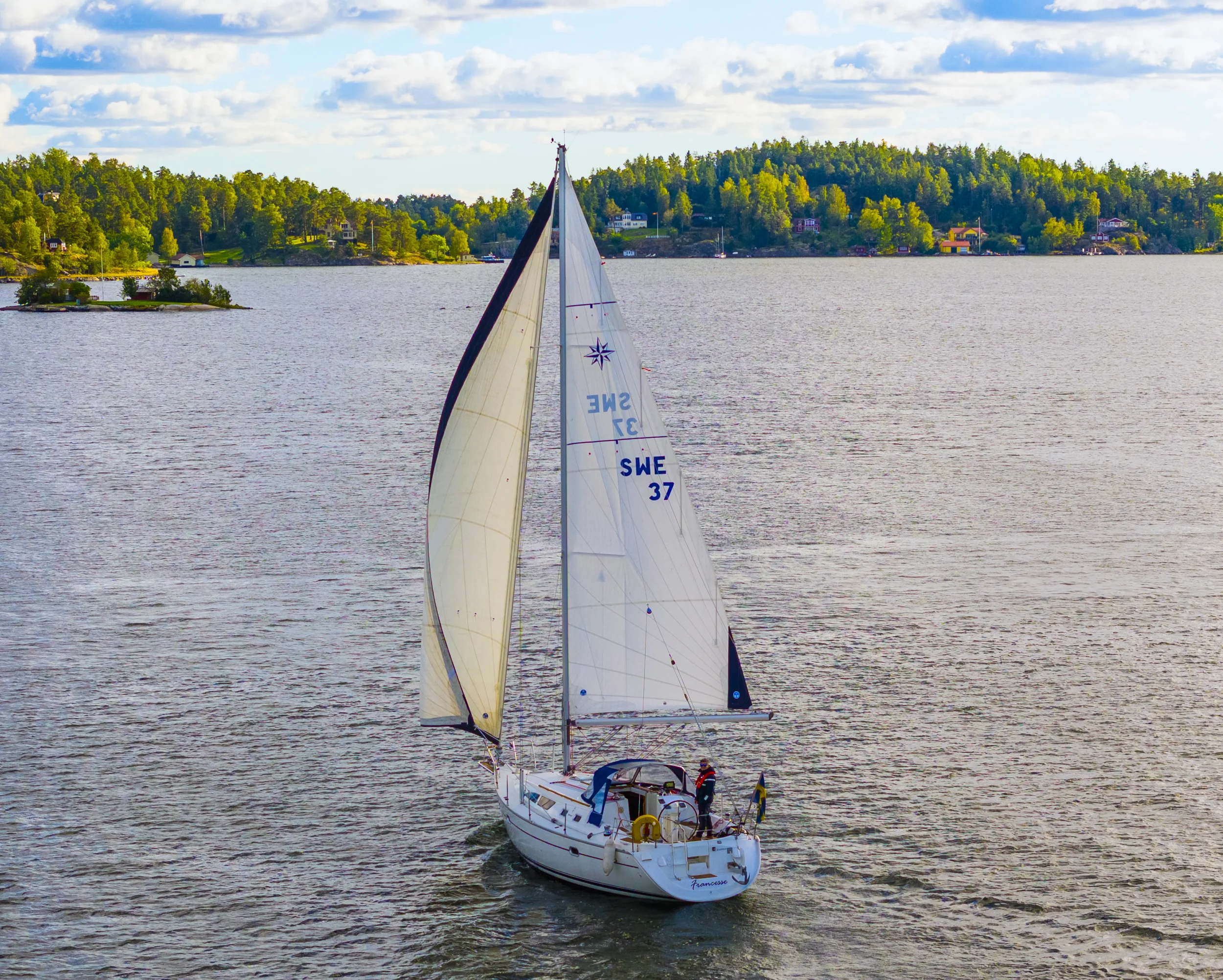 Zora at the helm of a customer's sailboat under way at sunset, Sweden