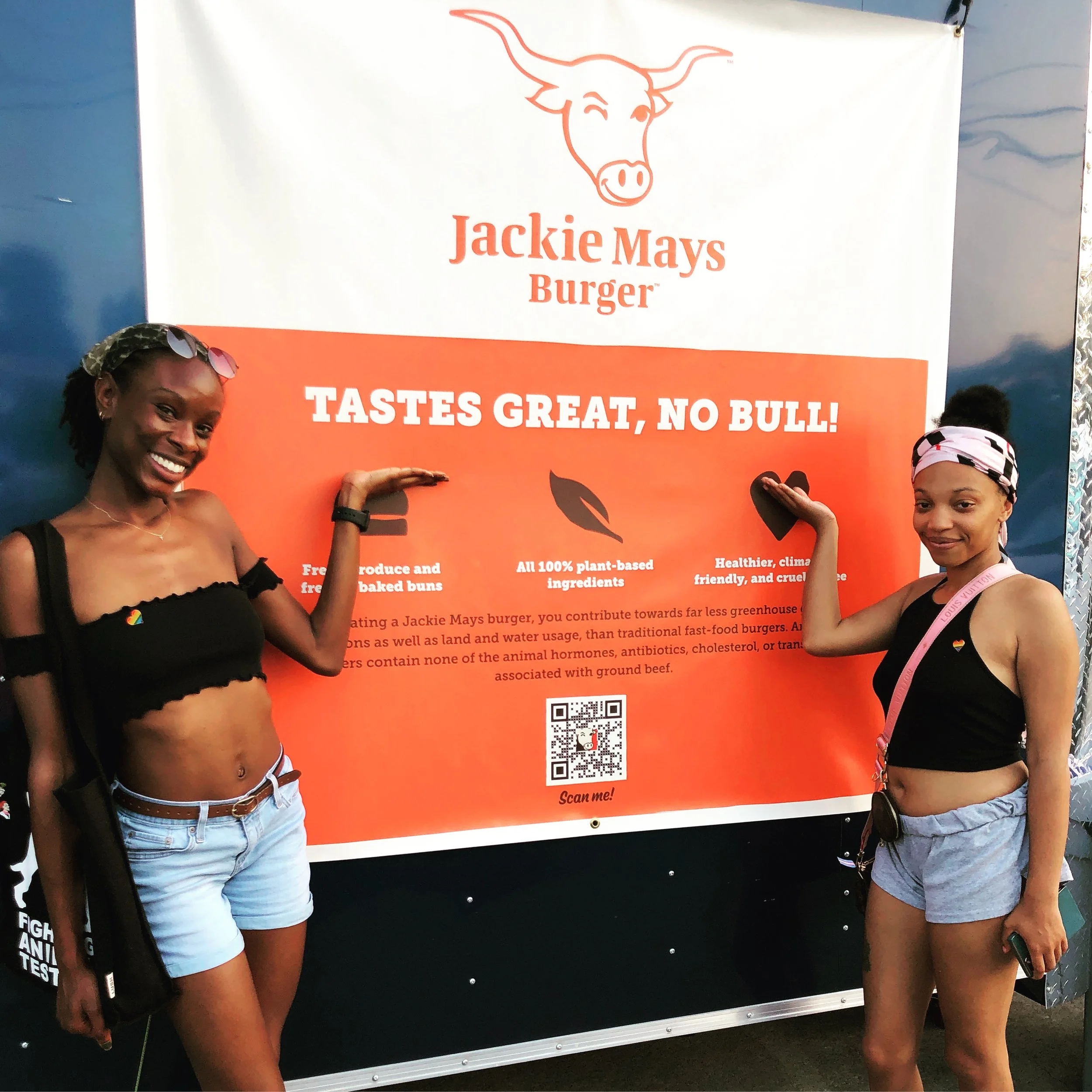 Two smiling customers presenting the Jackie Mays Burger "Tastes Great, No Bull!" banner