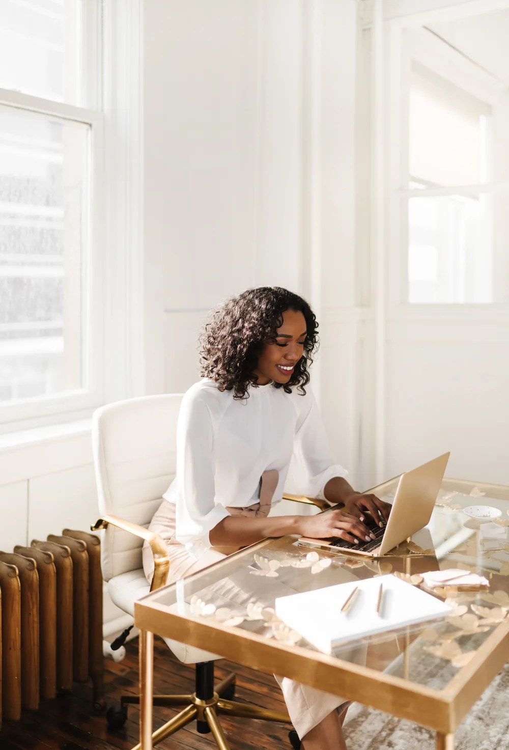A woman smiling at her laptop in a bright, calm office