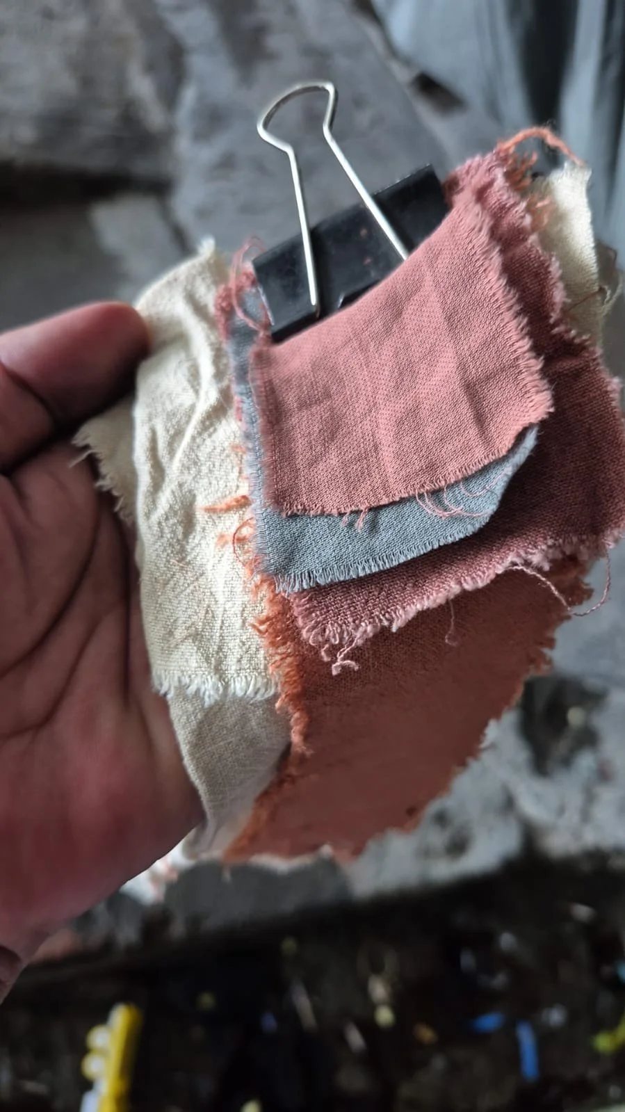 Hand holding a stack of hand-dyed fabric samples in the Nousa Concept Bali workshop