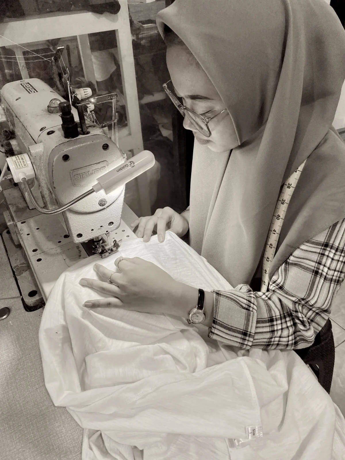 Tailor sewing with a measuring tape around her neck, Nousa Concept Bali workshop