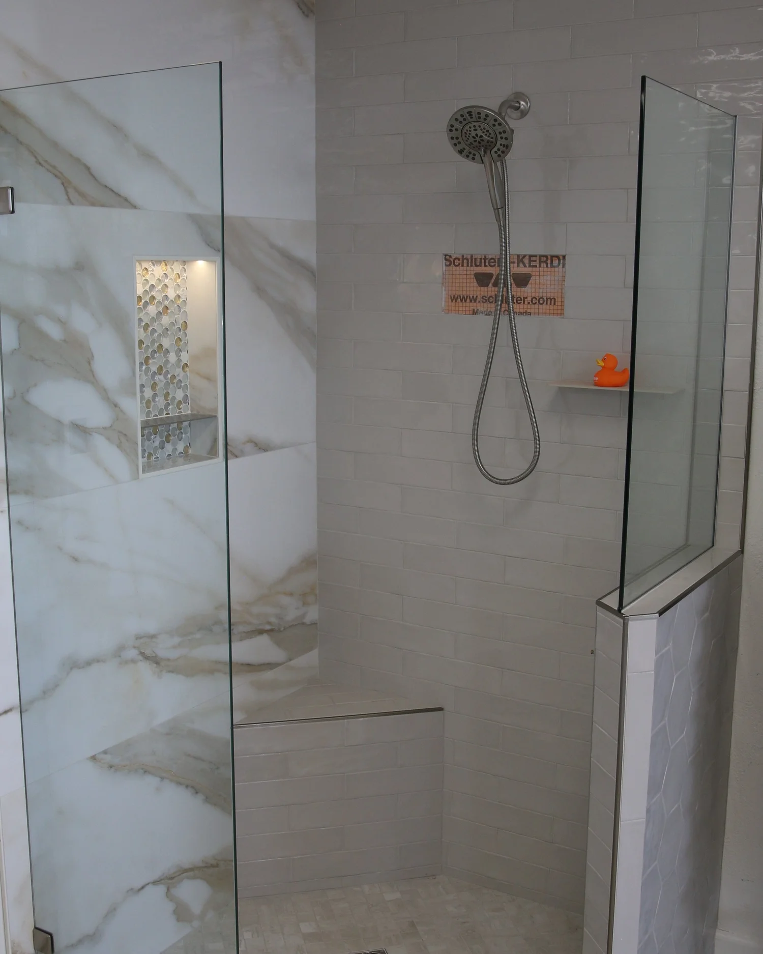 Full walk-in shower display with glass panels, bench, niche and mosaic floor