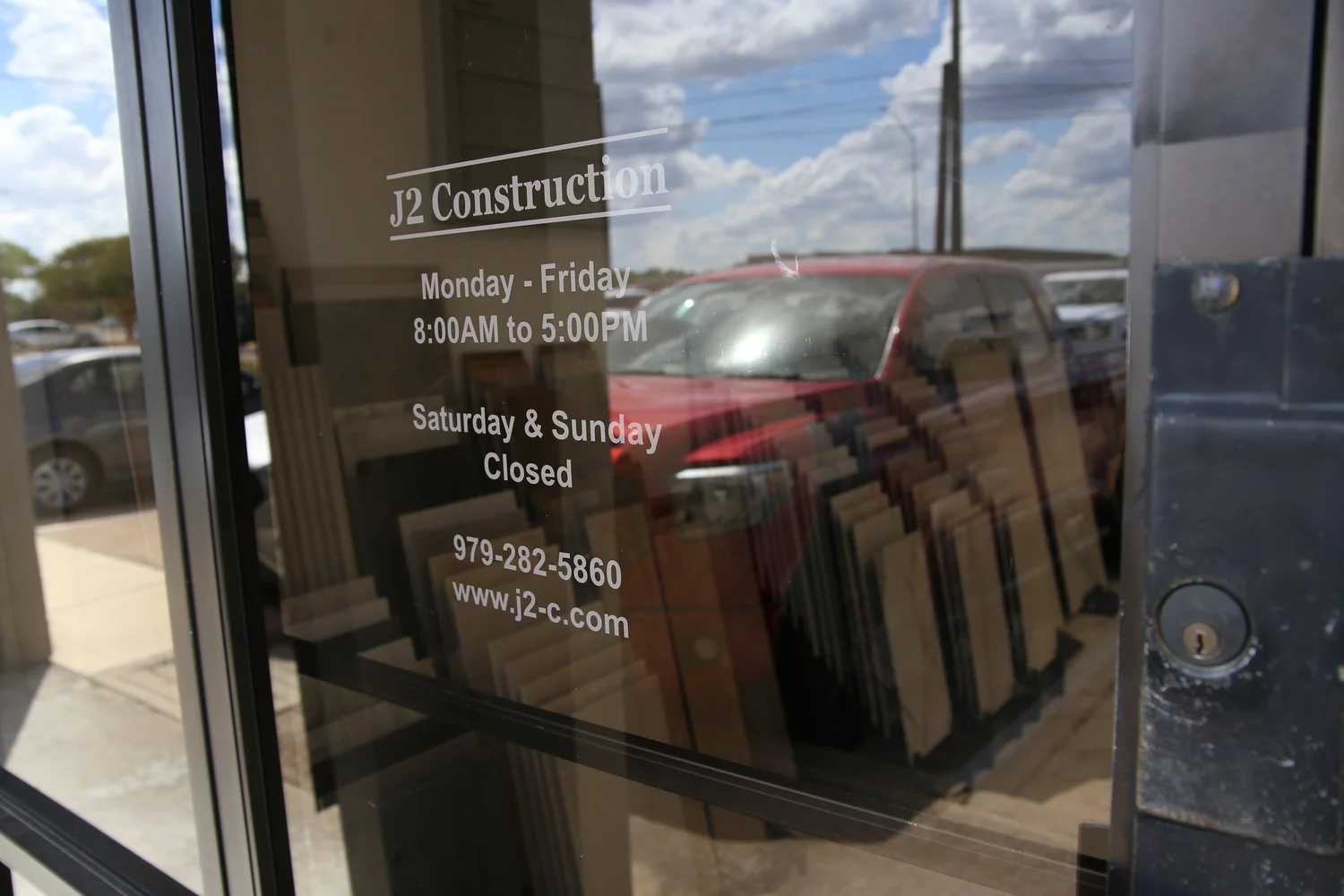 The J2 Construction showroom door, listing the opening hours