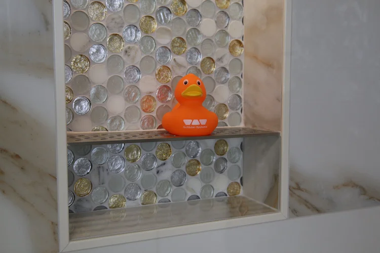 Glass mosaic accent tile in a finished shower niche