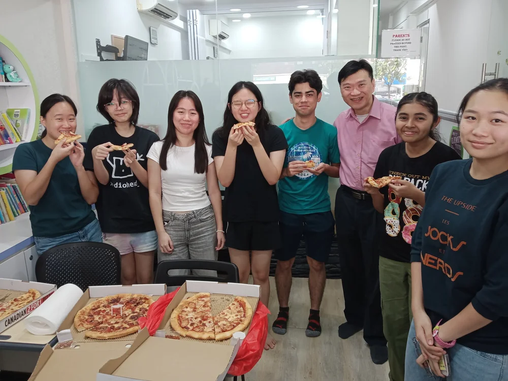 Mr Darrin Tan with smiling secondary students at a class celebration at KnowledgeTrail, Upper Thomson
