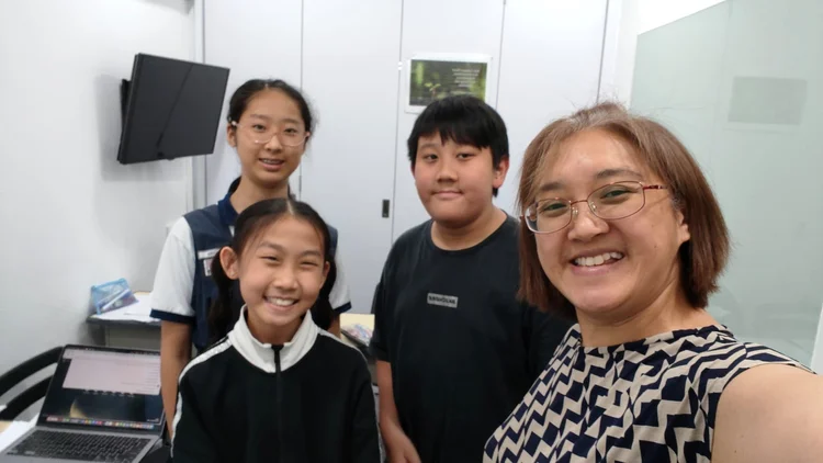 Mrs Charissa Tan with smiling primary students at KnowledgeTrail