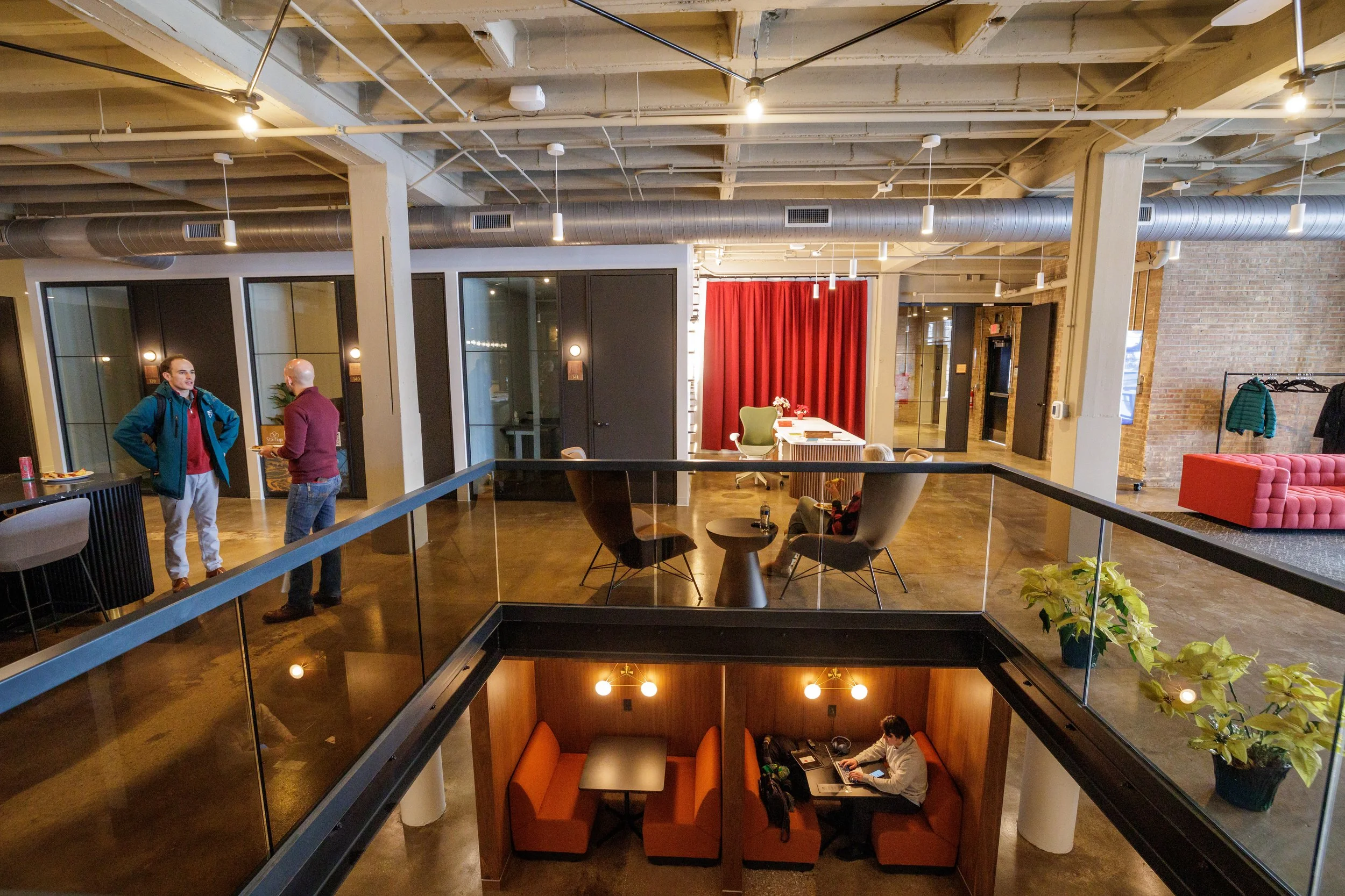 Momentum's two-story atrium with glass railings, booths, and exposed brick