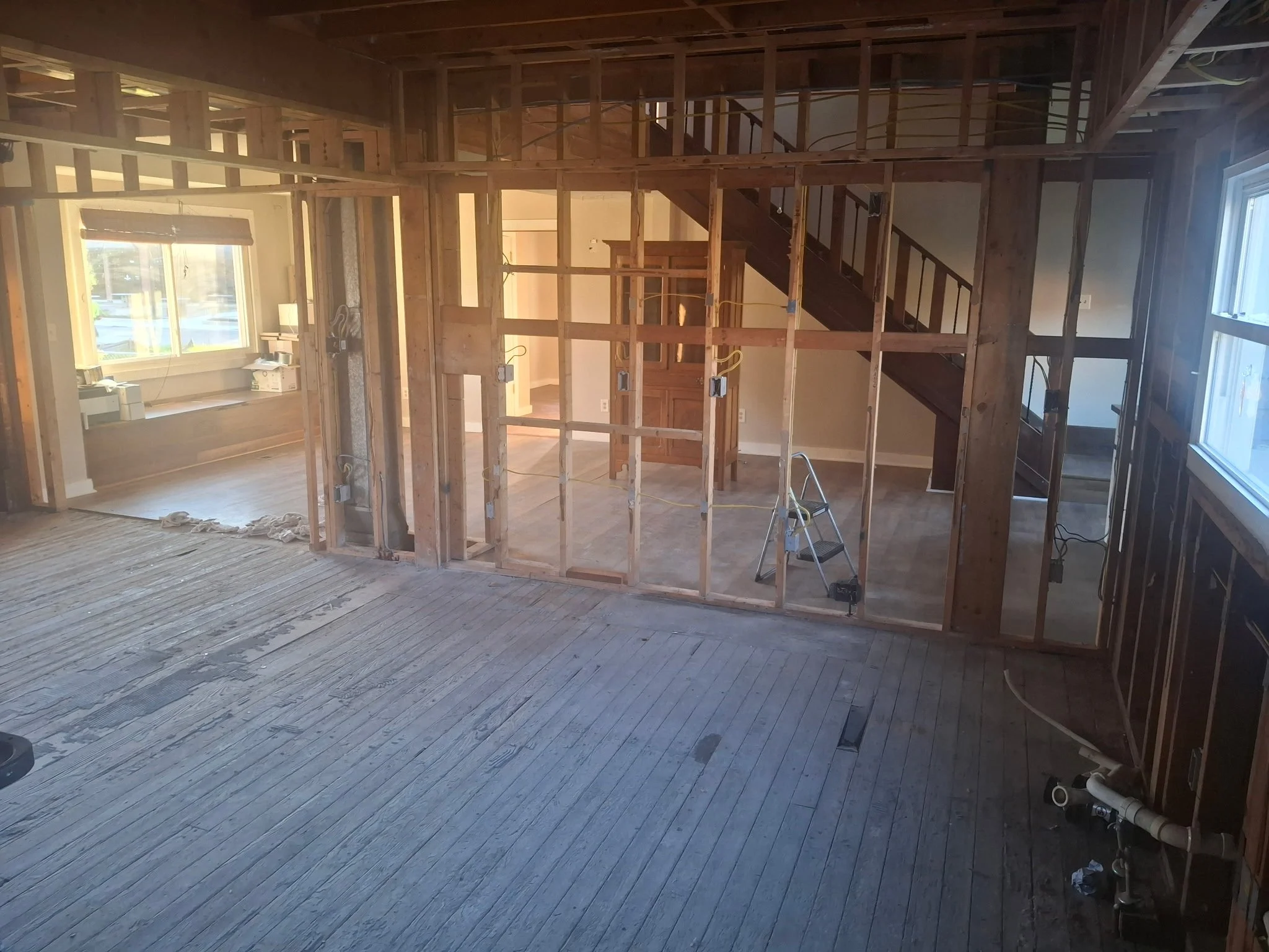 Main interior area of the parsonage with exposed walls, staircase, and flooring.