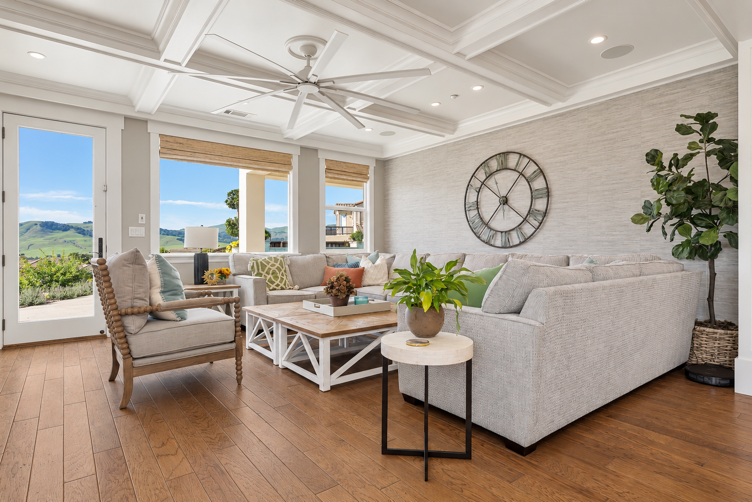 Fairfield family room with a gray sectional, wood floors, coffered ceiling, and windows overlooking green hills.