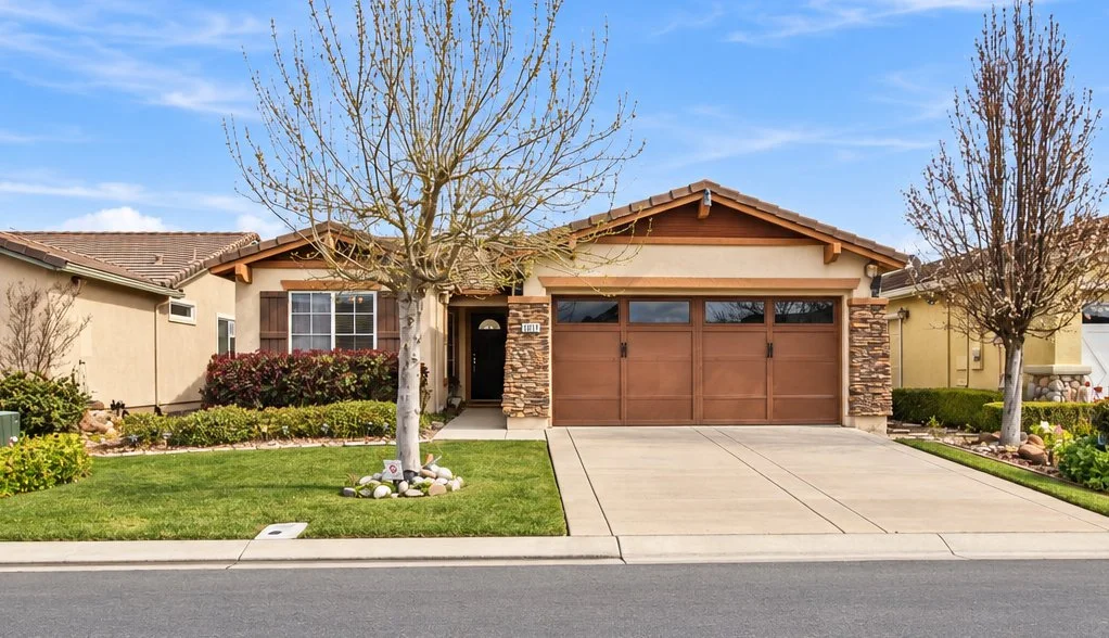 Front exterior of a single-story Rio Vista home with a tile roof, stone accents, two-car garage, and landscaped lawn.
