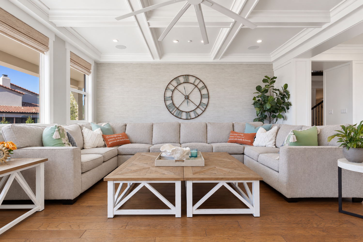 Gray sectional sofa and two wood coffee tables beneath a coffered ceiling in a bright Fairfield living room.