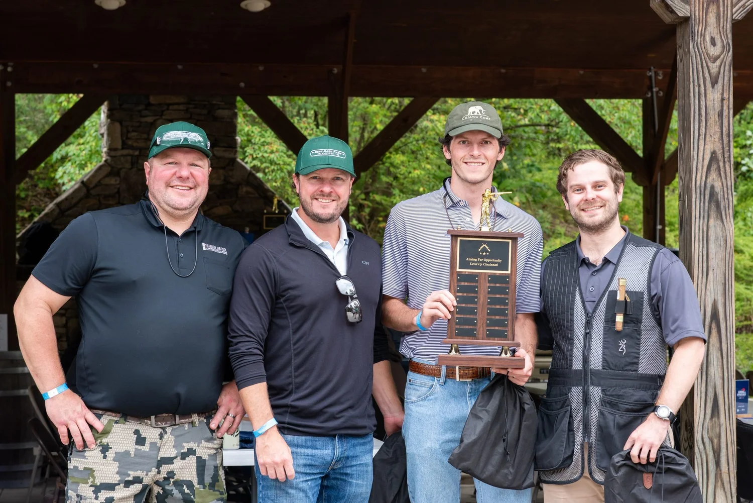 A team holds the Aiming for Opportunity trophy under the pavilion