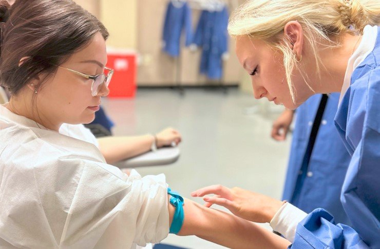 a female phlebotomist patiently serves her patient
