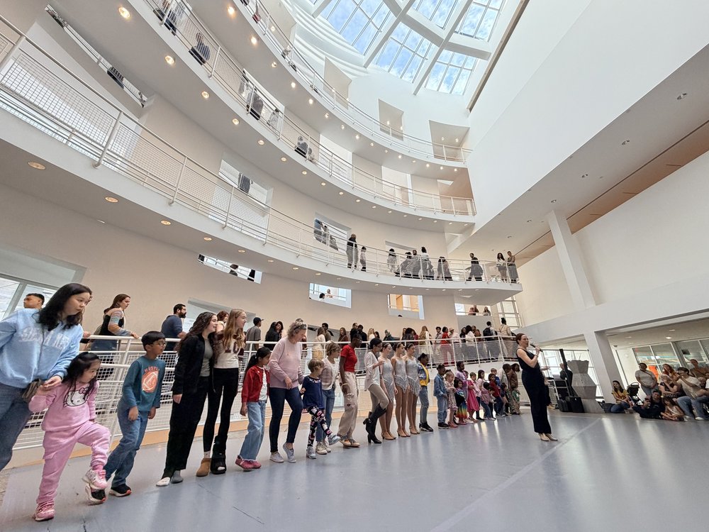 Dancers leading a line of community members through the High Museum atrium