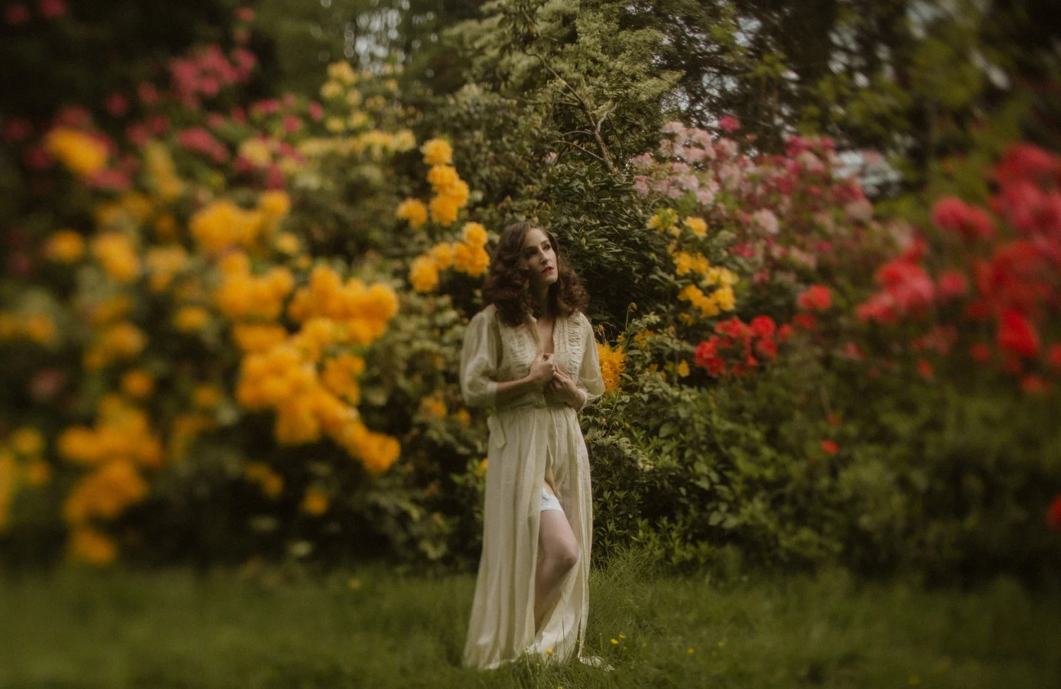 Woman in a vintage robe before blooming rhododendrons