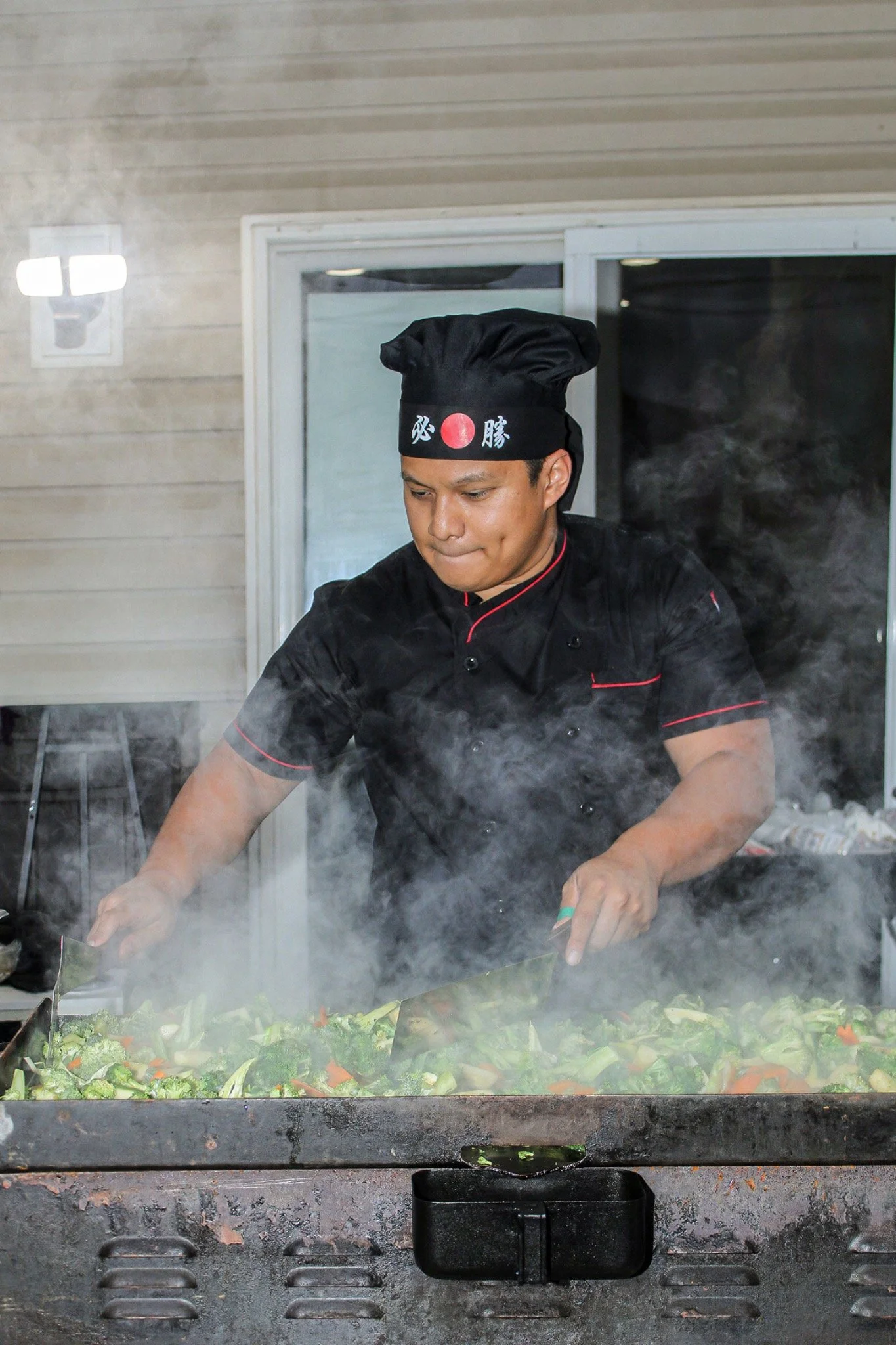 Chef tending vegetables on the steaming hibachi grill