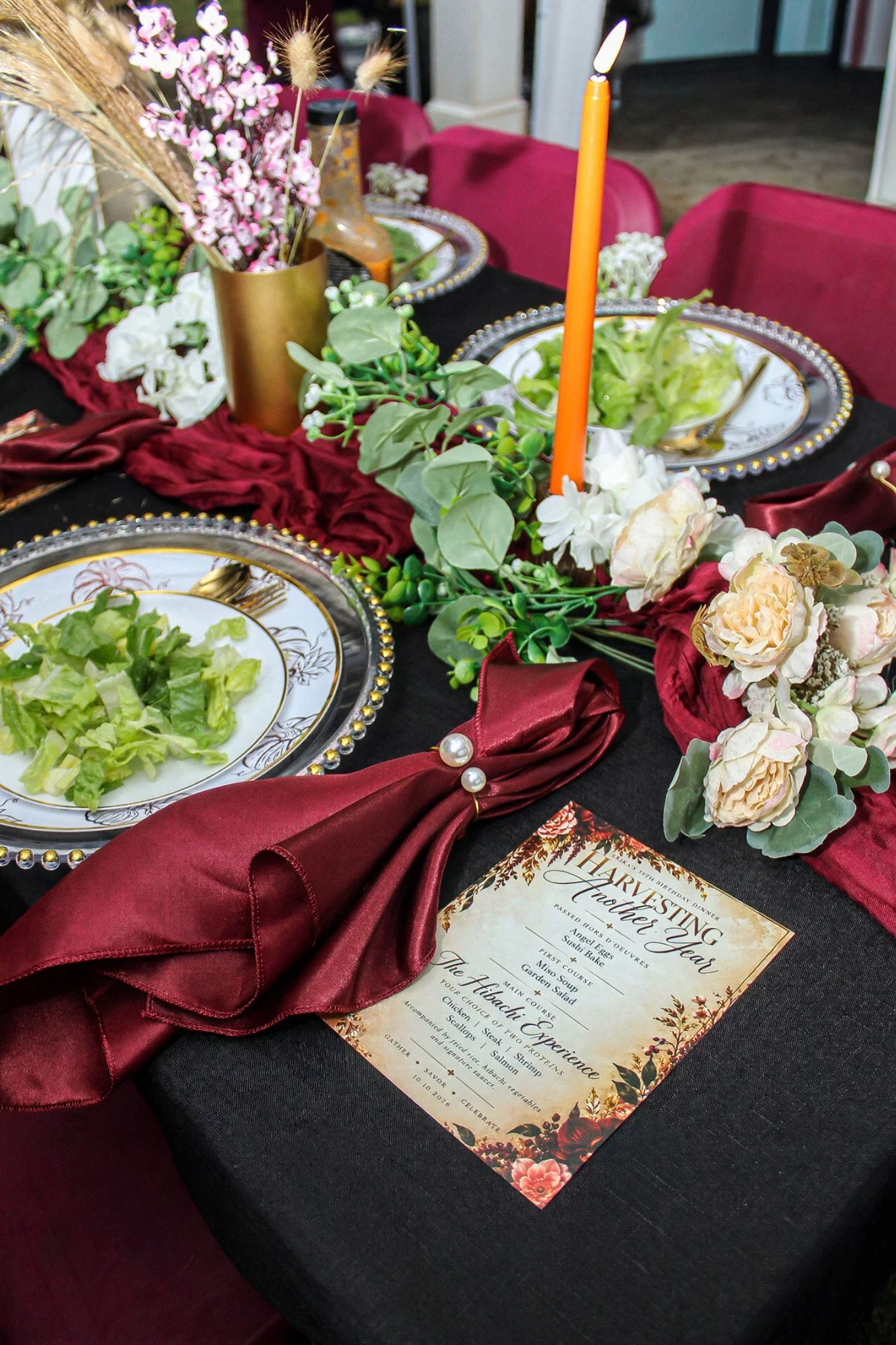 Floral centerpiece, gold-rimmed plates and burgundy napkins