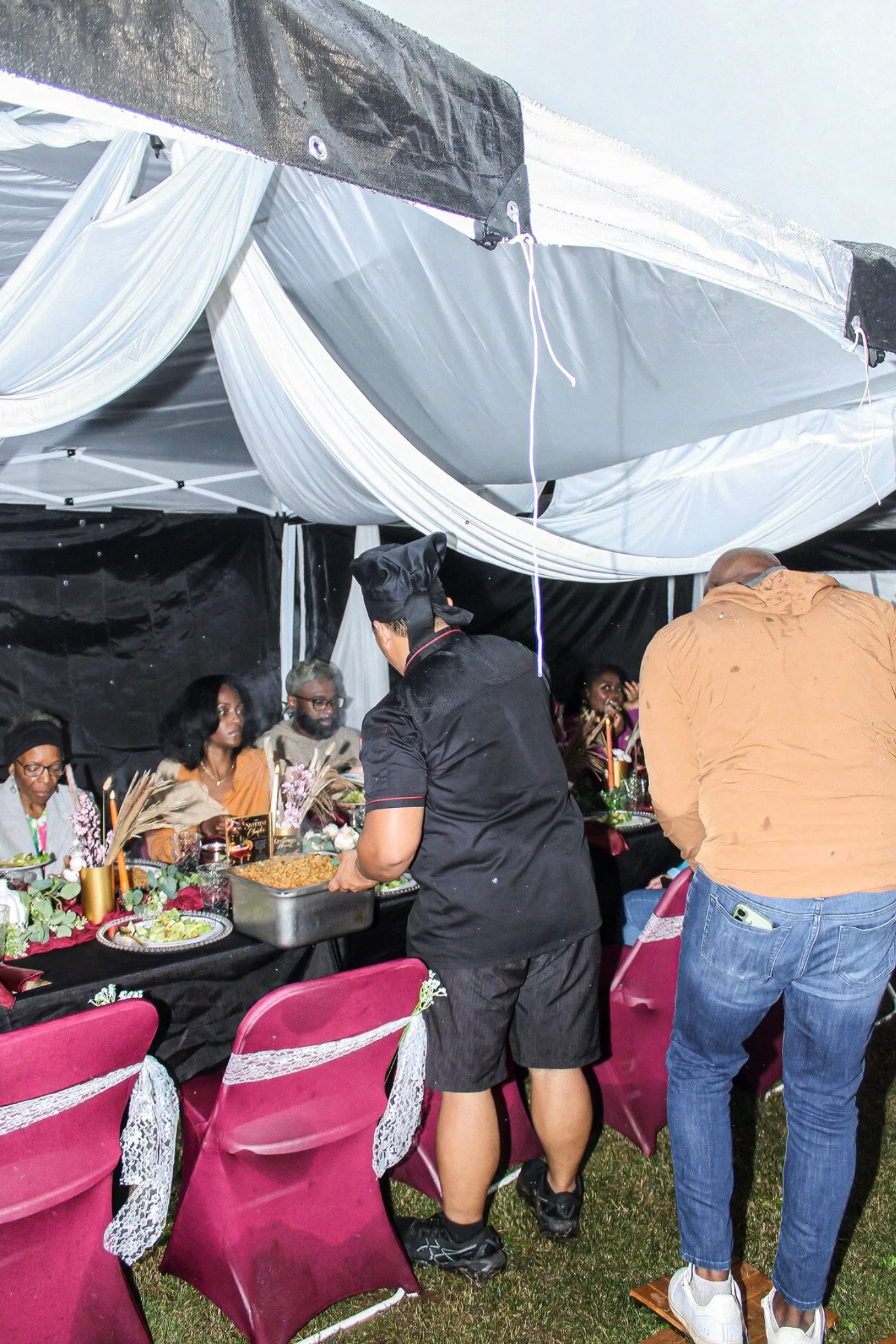 Hibachi chef serving guests beneath the draped tent
