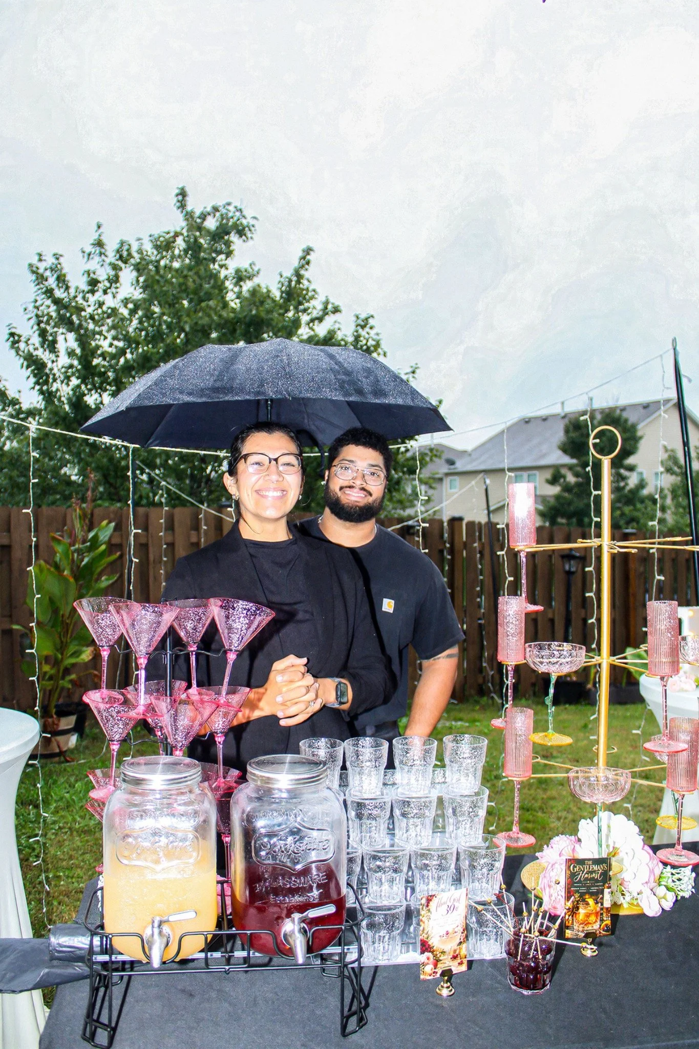 Two guests behind the blush glassware bar display